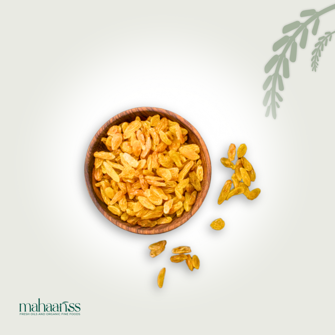 Wooden bowl filled with natural golden raisins and some raisins scattered on a light background