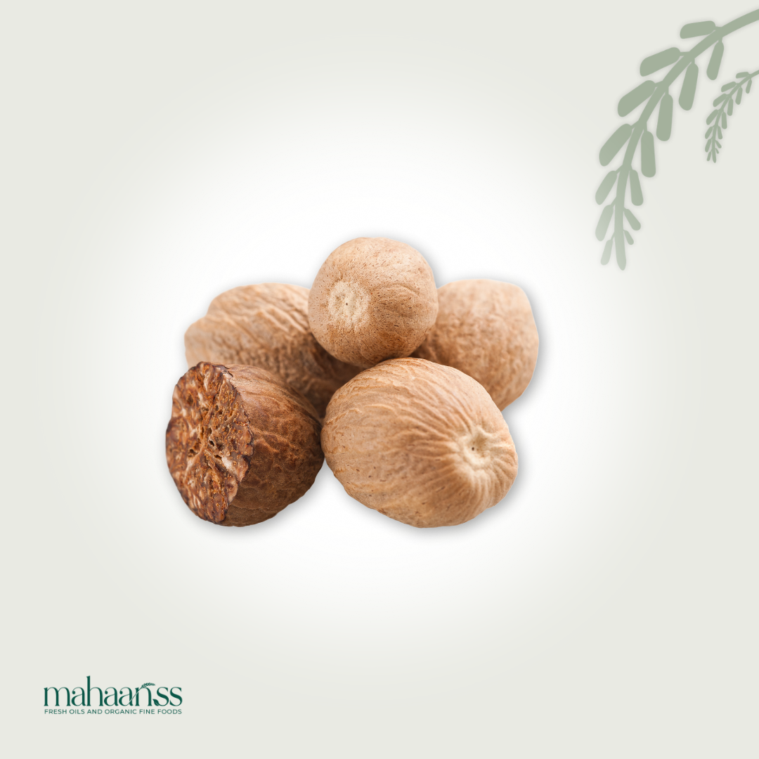 Whole natural nutmeg seeds pile with one cut open on a light background