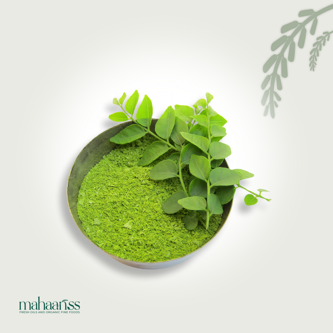 Bowl of natural curry leaf powder with fresh curry leaves on white background