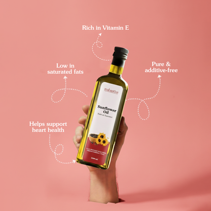 Bottle of sunflower oil held by a hand with health benefits text on a pink background